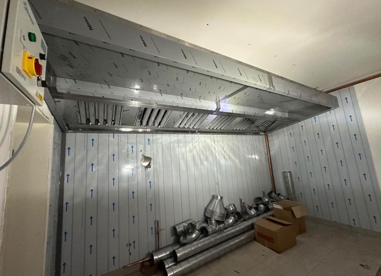 Stainless steel extraction canopy with baffle filters and spiral ductwork ready for connection in a commercial kitchen