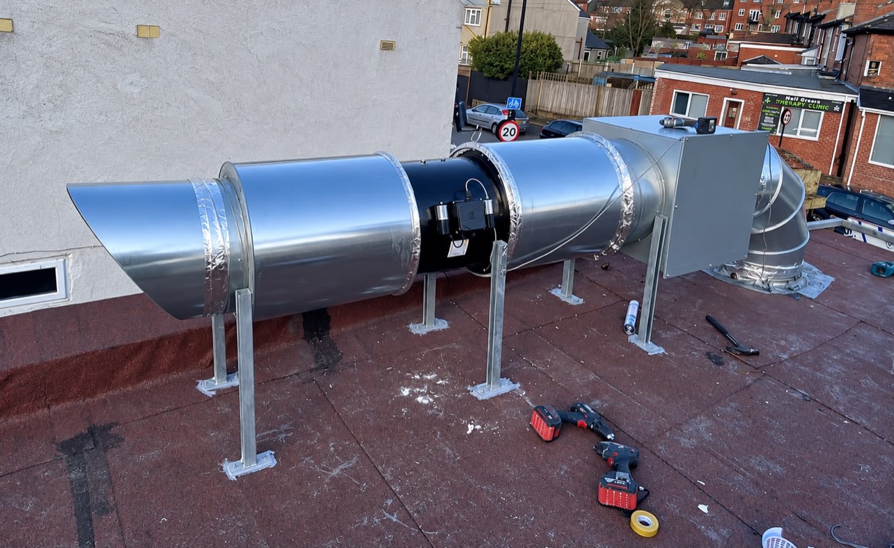 Roof-mounted extract fan and attenuator on galvanised stands above a commercial kitchen